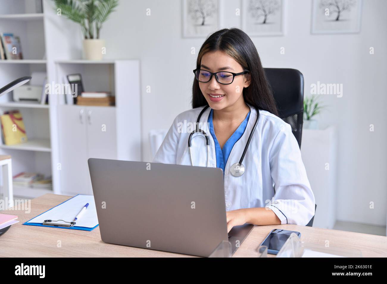 Junge asiatische weibliche Arzt Blick auf Laptop-Bildschirm hält Online-Konsultation Stockfoto