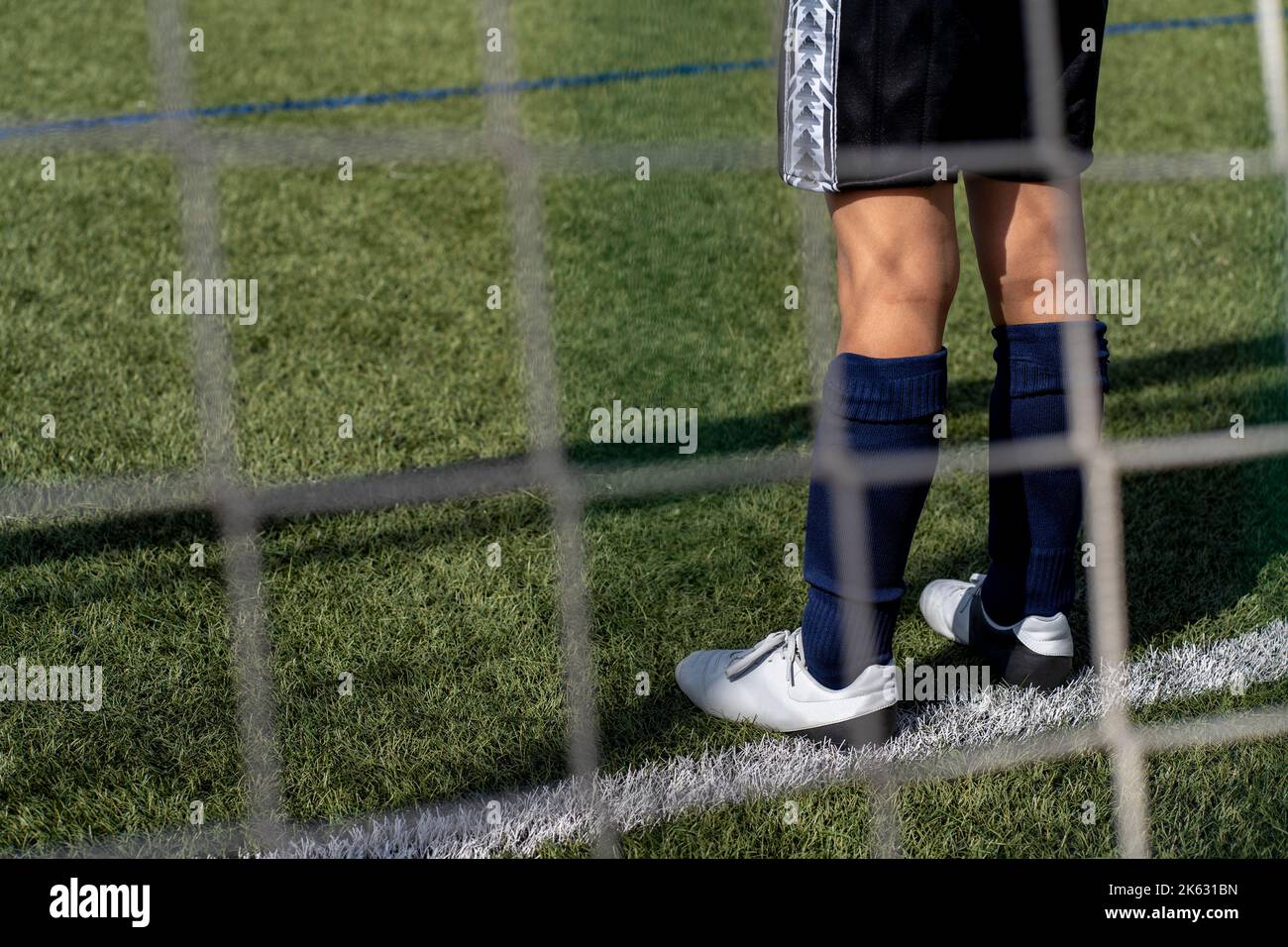 Nicht erkennbarer Fußball-Torwart im Tor des Kunstrasenfußballfeldes in einem Kinderwettbewerb. Stockfoto