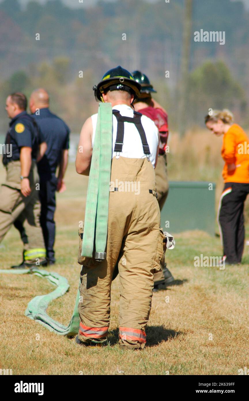 Feuerwehrmänner bekämpften ein Buschfeuer in der Gegend von Atlanta mit Wasser und Sicherheitsausrüstung und einem Spiralschlauch seiner Schulter in Hosenträgern Stockfoto