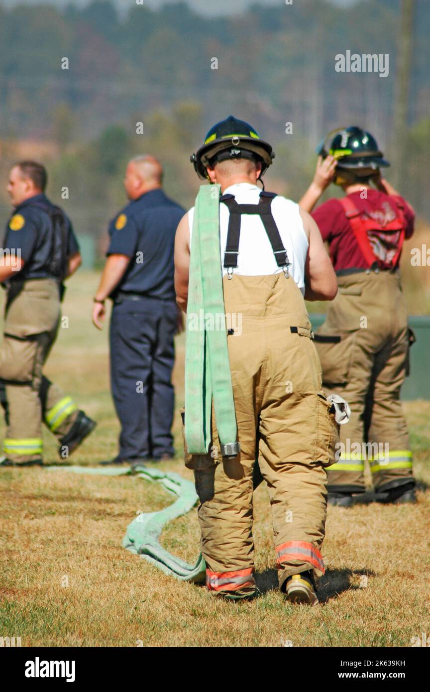 Feuerwehrmänner bekämpften ein Buschfeuer in der Gegend von Atlanta mit Wasser und Sicherheitsausrüstung und einem Spiralschlauch seiner Schulter in Hosenträgern Stockfoto