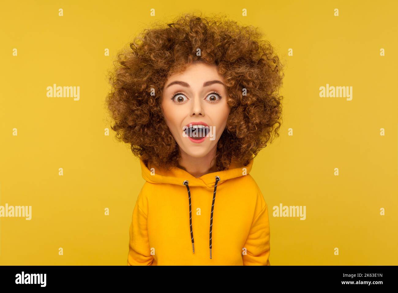 Wow, unglaublich. Comic-Porträt von schockiert überrascht lustige Frau mit Afro-Frisur Blick auf die Kamera mit offenem Mund und erstaunt großen Augen. Innenaufnahme des Studios isoliert auf gelbem Hintergrund. Stockfoto