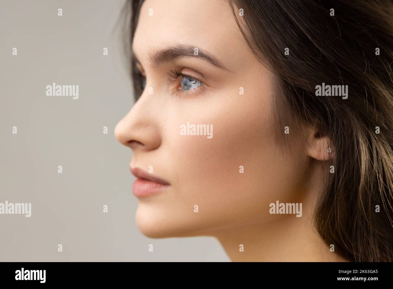 Seitenansicht Schönheitsporträt der schönen Frau mit perfekter Haut, Blick weg mit nachdenklichen Ausdruck, tragen lässigen Stil Jacke. Innenaufnahme des Studios isoliert auf grauem Hintergrund. Stockfoto