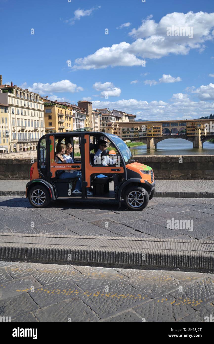 Touristen auf Eco Florence Tour im Elektroauto über Ponte Santa Trinita in Florenz Italien Stockfoto