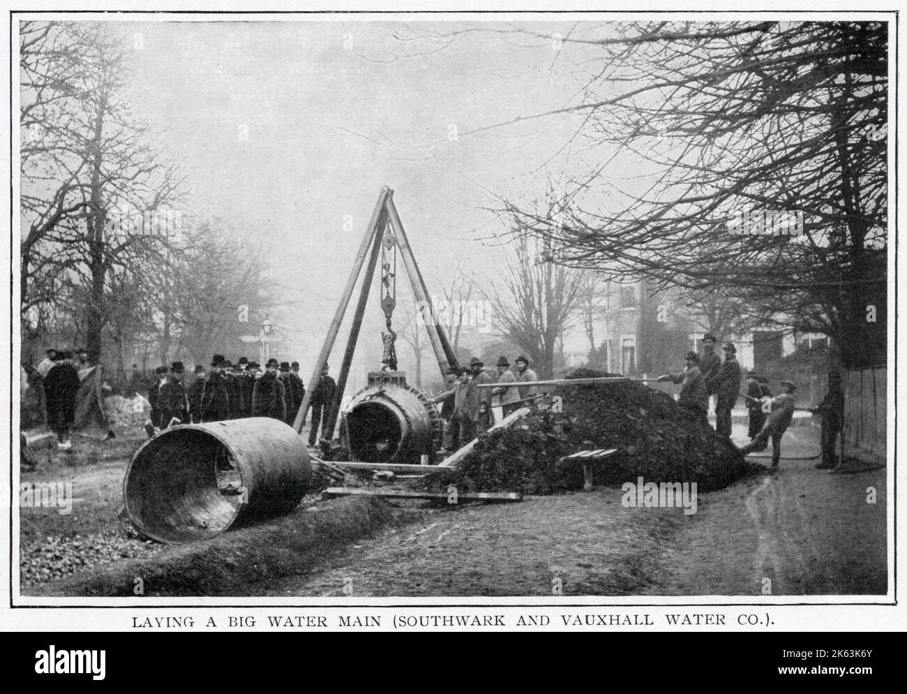 Das Foto zeigt Ingenieure und Assistenten, die schwere, kreisförmige Rohrleitungen mit einem Kran in den Straßen von Süd-London unterirdisch anheben. Das war eine gewaltige Aufgabe, die in ganz London stattfand, um die Gemeinde mit frischem Wasser zu versorgen. Stockfoto