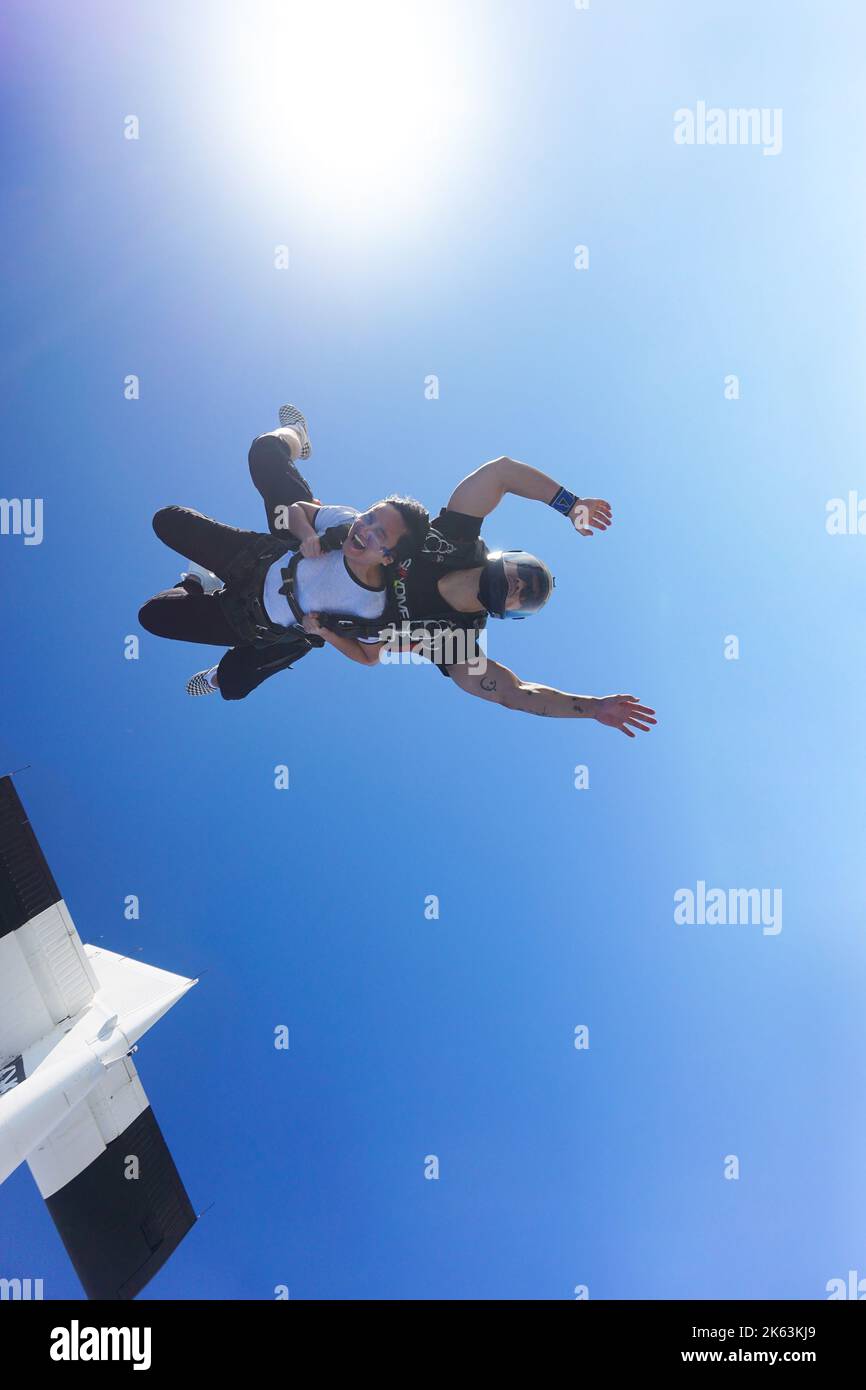 Tandem-Fallschirmspringer springen aus dem Skydive Dubai-Flugzeug in einen wilden freien Fall aus 13.000 Metern Höhe. Anfänger, die sich dem Instruktor zunutze machen, schreit vor Aufregung. Stockfoto