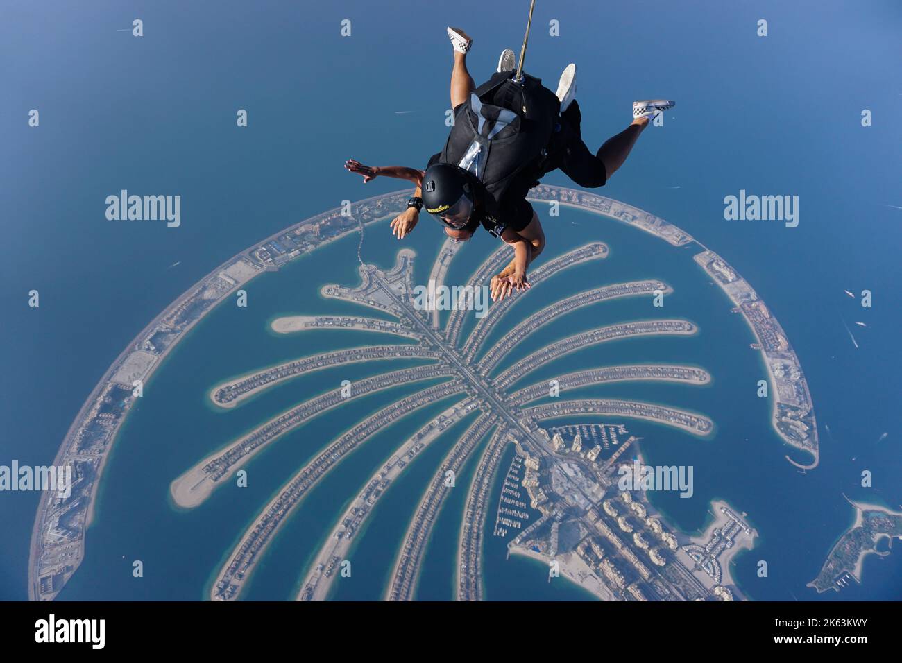 Tandem-Fallschirmspringer schweben über Palm Jumeirah, einer berühmten künstlichen Insel, eine wichtige Attraktion und Wahrzeichen der modernen Stadt Dubai, Vereinigte Arabische Emirate. Stockfoto