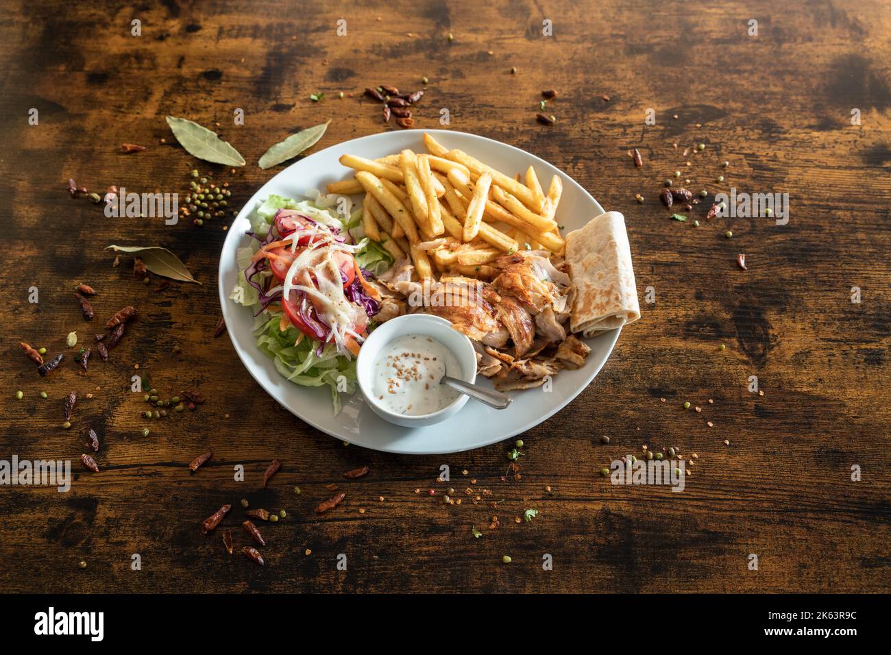 Kebab-Teller mit französischen Fries und weißer Sauce auf einem Holztisch Stockfoto