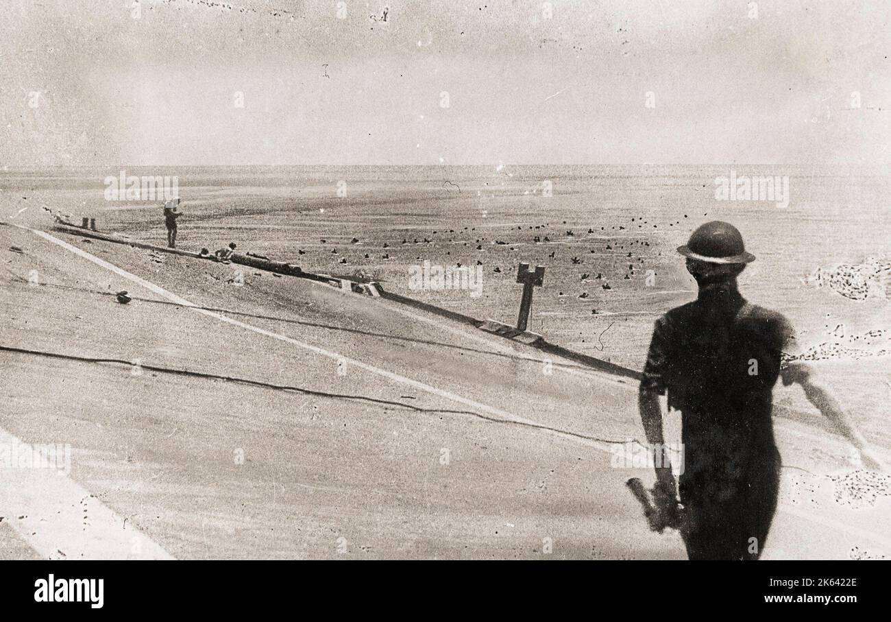 Vintage-Foto des Zweiten Weltkriegs - letzter Moment der HMS Hermes, schräg nach Angriff japanischer Tauchbomber kippend, 1942 - Matrosen im Meer, negatives Wasser beschädigt Stockfoto