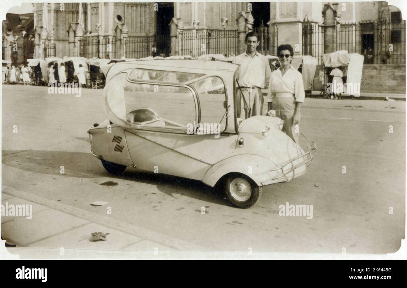 Ein junges (möglicherweise) italienisches Paar, das stolz neben seiner Messerschmitt kr200 steht, oder Kabinenroller (Cabin Scooter), ein dreirädriges Luftpolsterauto, das vom Flugzeugingenieur Fritz fend entworfen und von 1955 bis 1964 in der Fabrik des deutschen Flugzeugherstellers Messerschmitt hergestellt wurde. Stockfoto