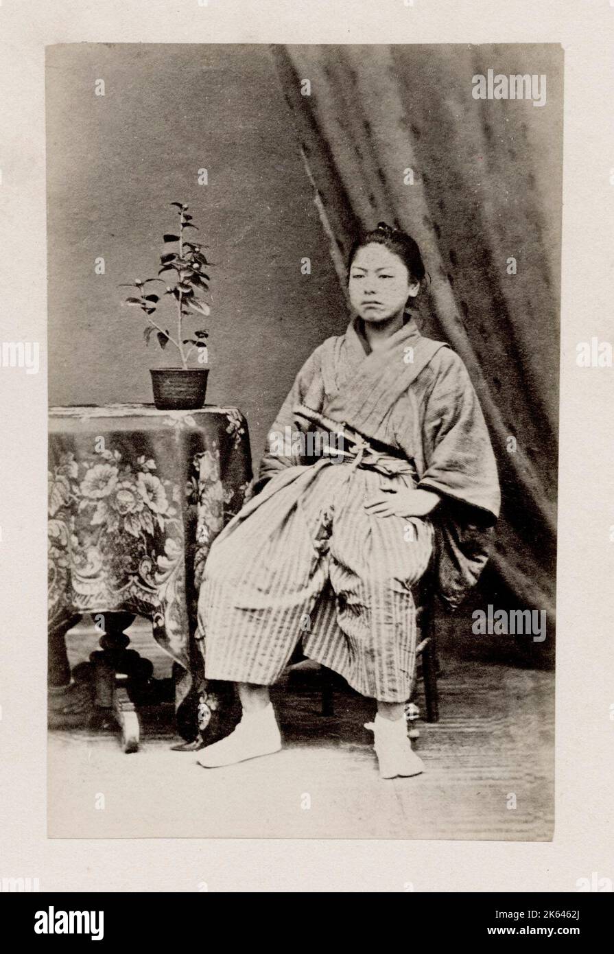 Vintage 19. Jahrhundert Fotografie - frühe fotografische Porträt aus Japan, wahrscheinlich das Werk der japanischen Fotografin Shimooka Renjo - sitzender Mann mit Schwert. Stockfoto