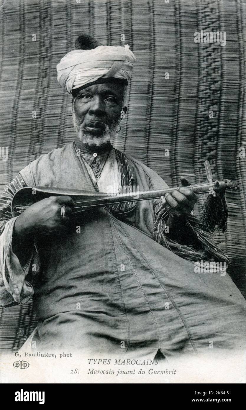 Ein älterer marokkanischer Mann, der einen Sünder spielt, auch bekannt als Guembri, Gimbri oder Hejhouj, ist eine dreireihige, hautbedeckte Basslaute, die von den Gnawa-Leuten benutzt wird. Sie ist etwa so groß wie eine Gitarre, mit einem Körper, der aus einem Baumstamm geschnitzt und auf der Spielseite mit Kamelhaut bedeckt ist. Stockfoto