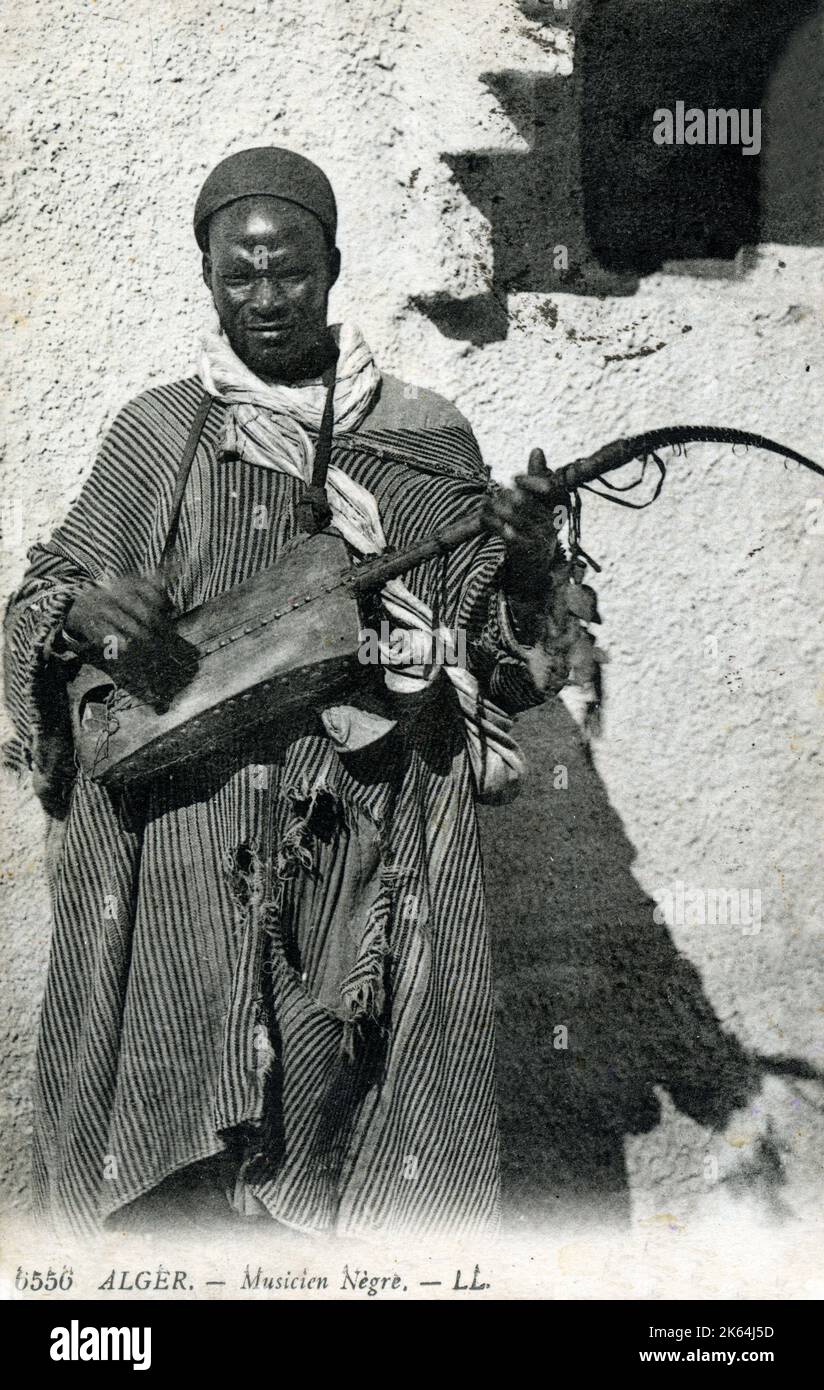 Algerien: Afrikanischer Gnawa-Musiker, der einen traditionellen Sünder spielt, auch bekannt als Guembri, Gimbri oder Hejhouj, eine dreireihige, hautbedeckte Bass-Laute. Stockfoto