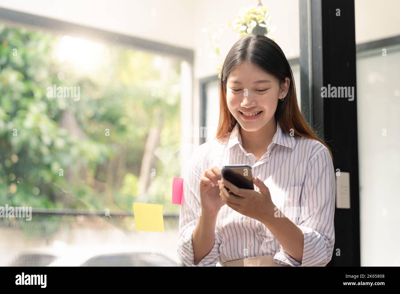 Eine schöne junge asiatische Frau, die Mobiltelefon hält und benutzt. Stockfoto