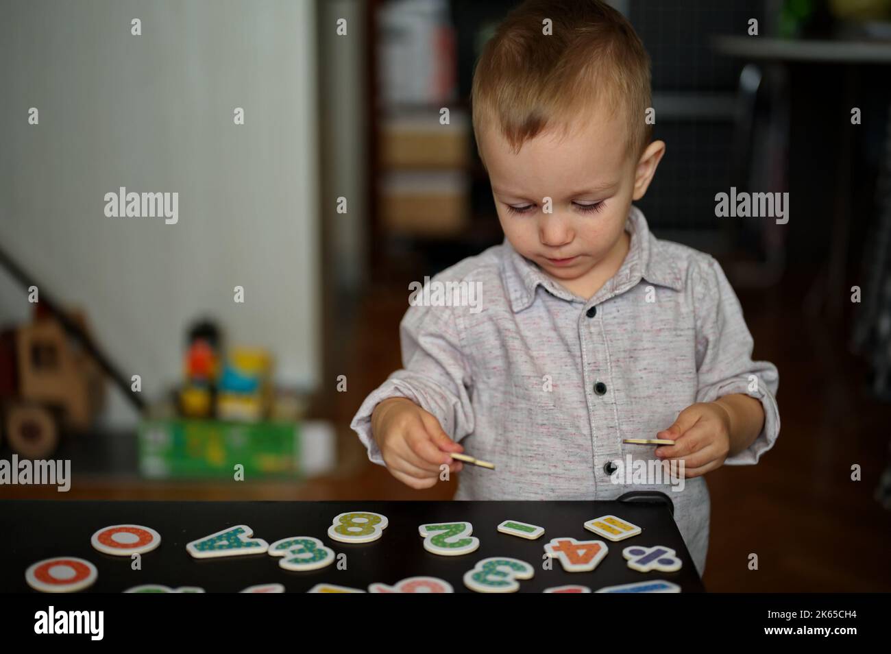 Porträt eines niedlichen kleinen Jungen, der mit Buchstaben und Zahlen auf einem Tisch spielt Stockfoto