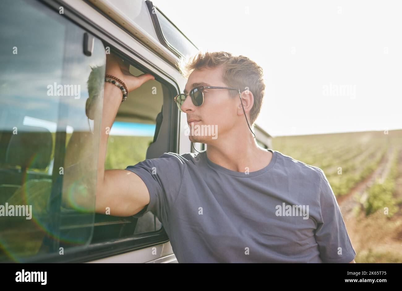 Reisen, Abenteuer und Mann mit seinem Auto auf dem Land während einer Roadtrip während der Sommerferien. Sonnenschein, im Freien und junger Mensch in der Natur Stockfoto