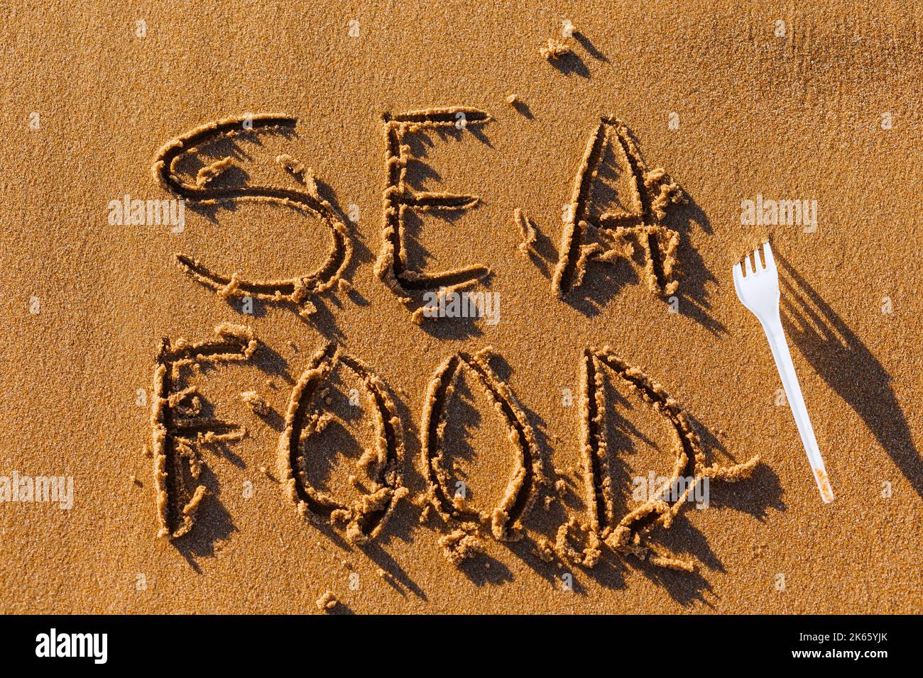 Das Wort Sea Food wird manuell auf den Sand geschrieben. Das Konzept der Meeresküche. Kulinarischer Hintergrund im Sommer. Stockfoto