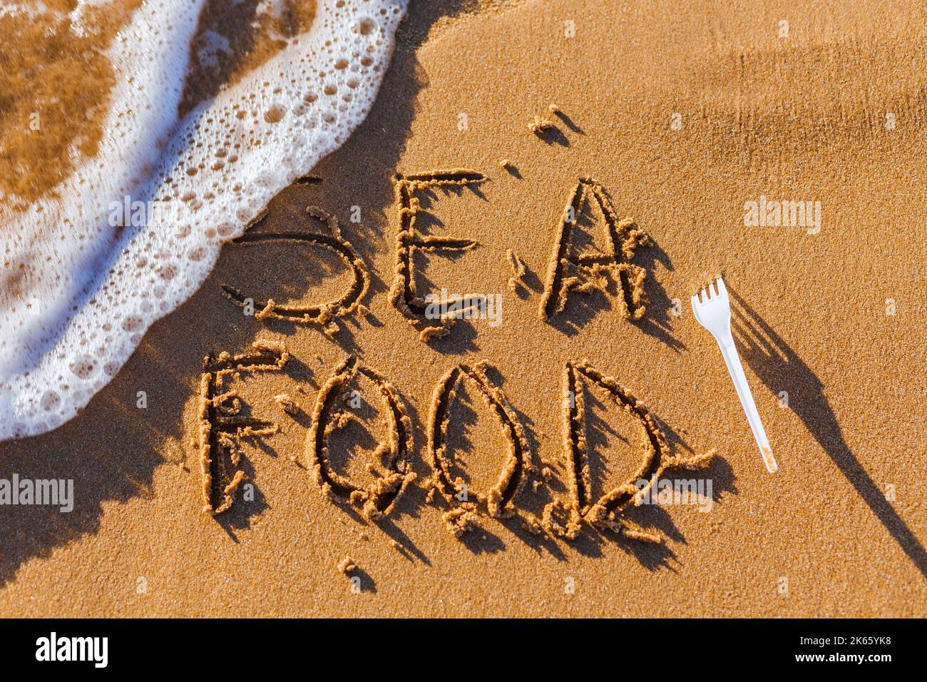 Das Wort Sea Food wird manuell auf den Sand geschrieben. Das Konzept der Meeresküche. Kulinarischer Hintergrund im Sommer. Stockfoto
