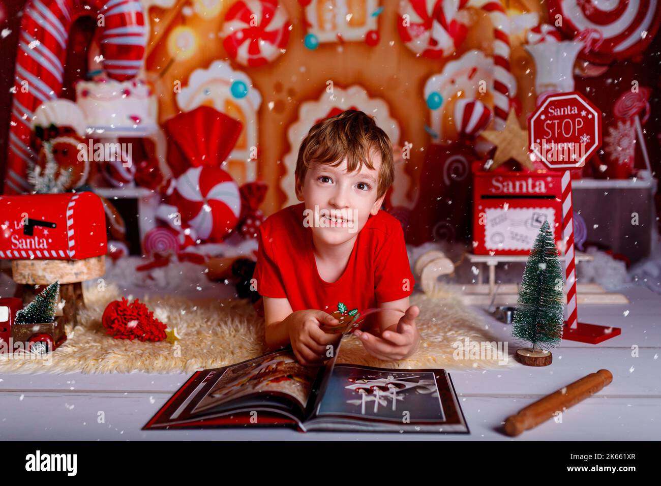 Kind liest zu Weihnachten ein Buch. Frohe Weihnachten und Neujahr, Winterurlaub Konzept mit auf rotem Hintergrund. Stockfoto