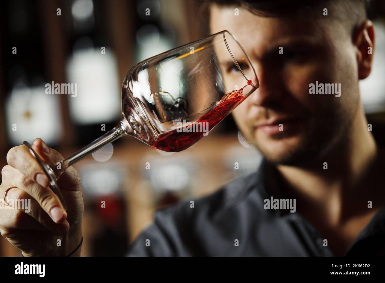 Bokal von Rotwein auf dem Hintergrund, männliche Sommelier schätzen Getränk Stockfoto