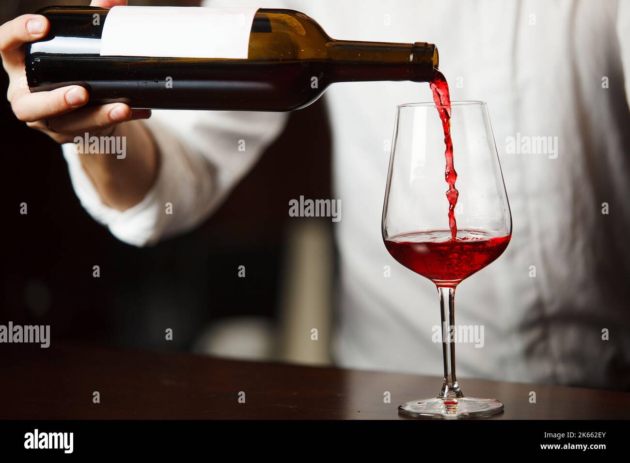 Sommeliermännchen gießt Rotwein in langstielige Weingläser. Stockfoto