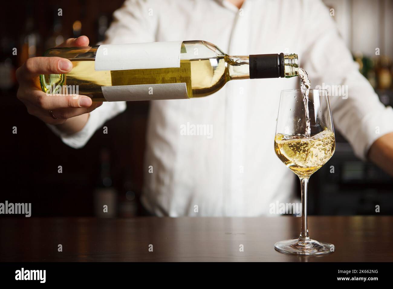 Sommeliermännchen gießt Weißwein in langstielige Weingläser. Stockfoto