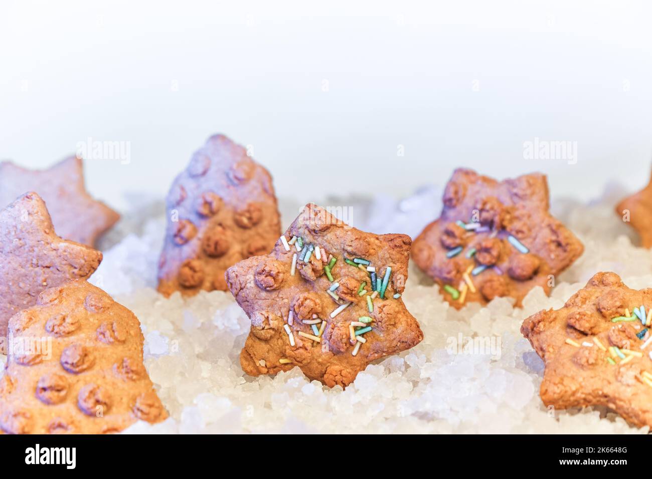 Weihnachts-Lebkuchenkekse in Form eines Sterns in dekorativem Schnee und Eis auf verschwommenem Hintergrund mit Feiertagsbäcken Stockfoto