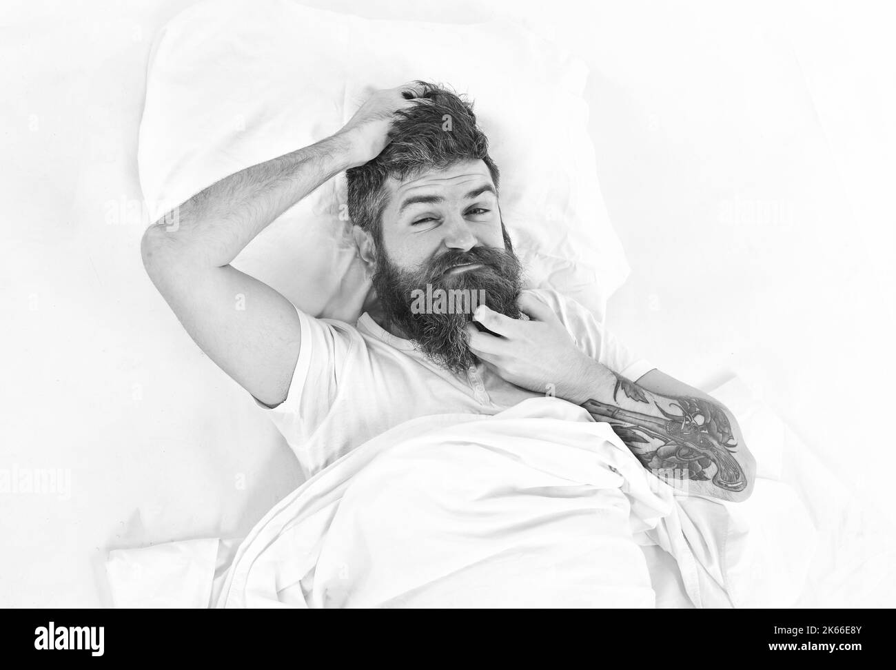 Mann mit juckenden Gesicht wacht auf, legt sich auf das Bett und kratzt Stockfoto