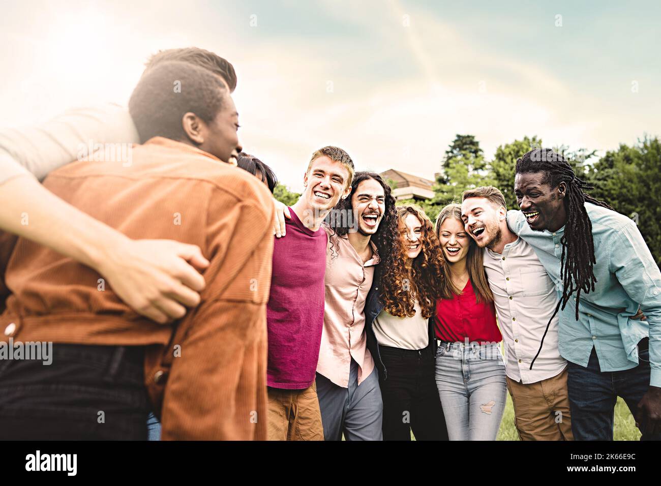 Multiethnische Gruppe von verschiedenen jungen Menschen, die Spaß daran haben, sich zusammenzuschließen, lachen und gemeinsam Arm an Schulter im Park zu interagieren - Einheit, Stockfoto