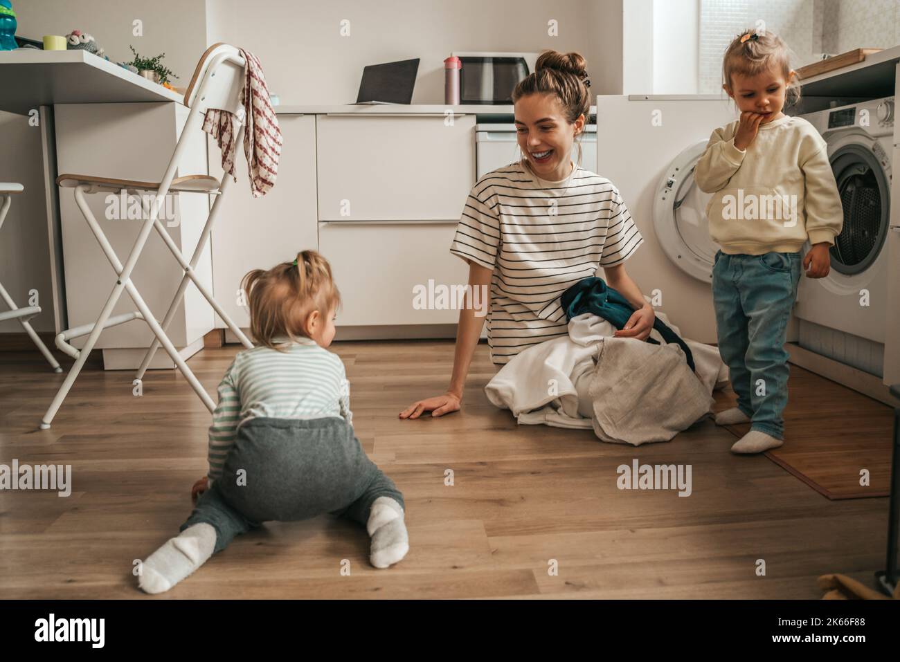 Eltern spielen mit Kindern und Wäschestücke für die Waschmaschine Stockfoto