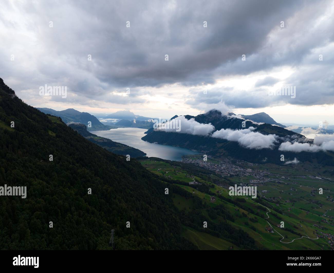 Schweizer Berg bei Sonnenuntergang Drohnenübersicht im Kanton Schwyz. Tief hängende Wolken über dem Bergsee bei Schwyz Zentralschweiz. Stockfoto