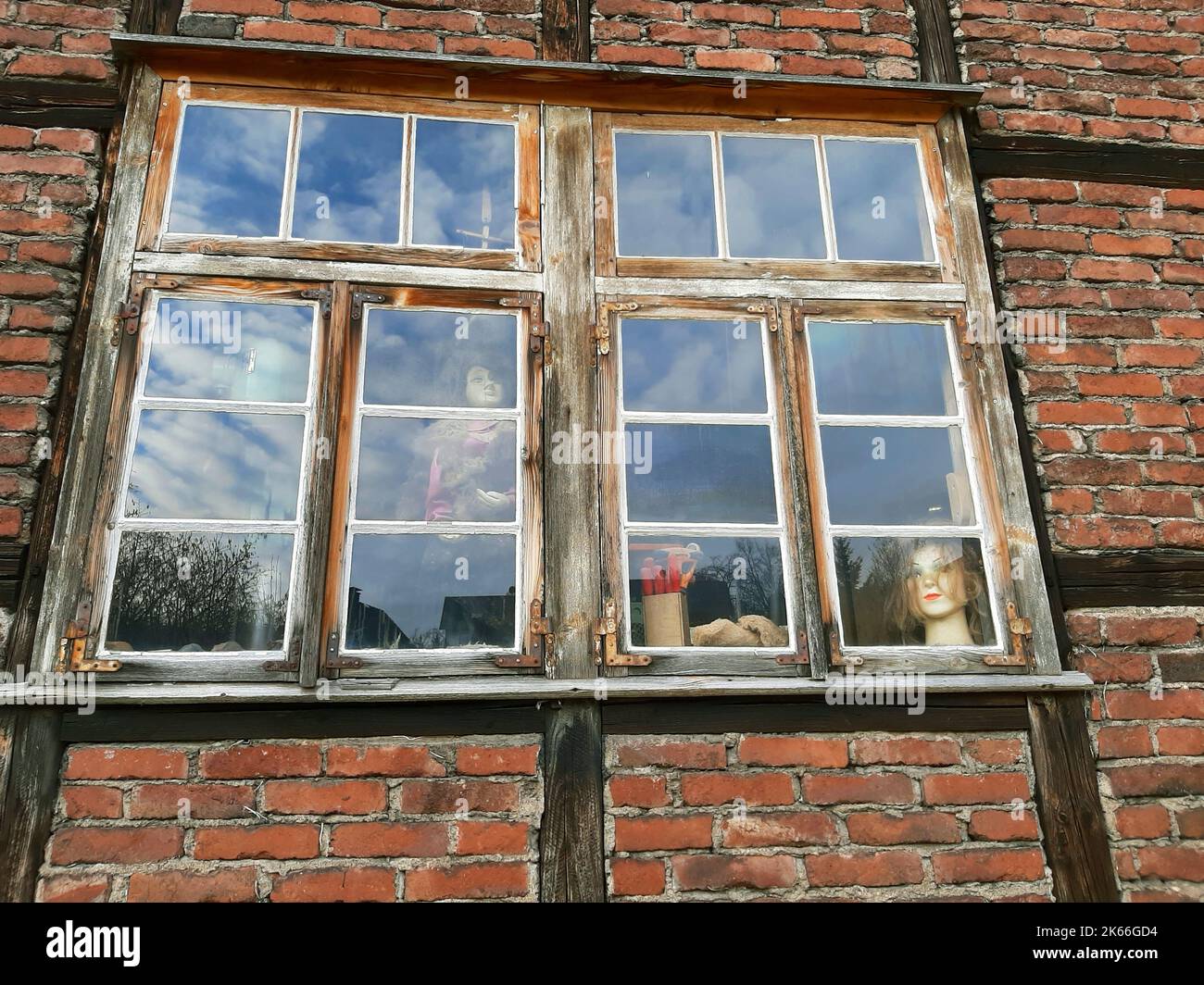 Altes Holzfenster eines Fachwerkhauses mit Puppenköpfen, Deutschland Stockfoto