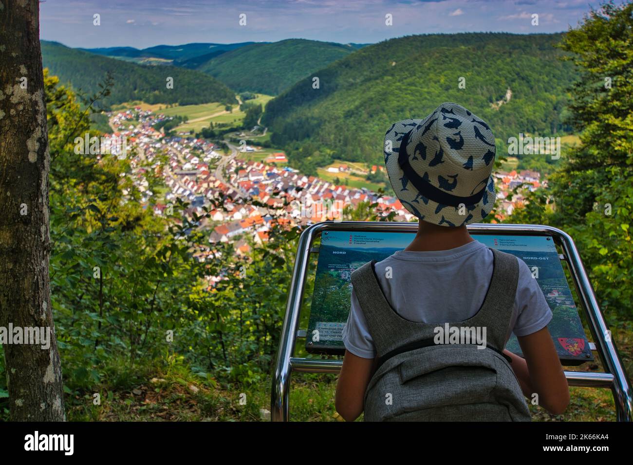 Kleiner Junge, der auf einem Hügel steht und auf eine farbenfrohe hügelige Sommerlandschaft in der Schwäbischen Alb herabblickt Stockfoto