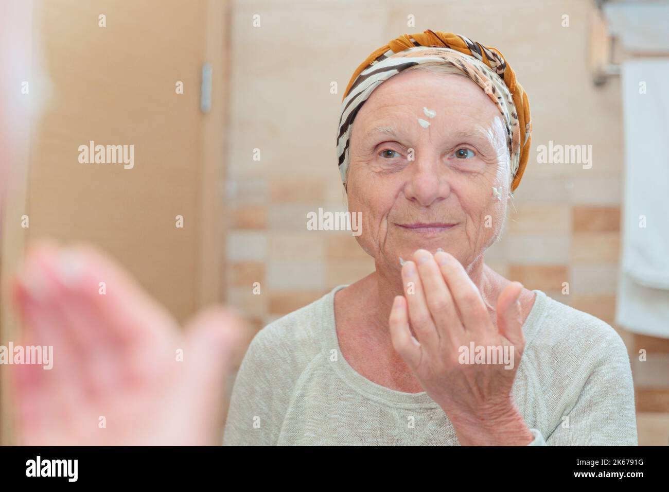 Ältere Frau, die sich um ihr Gesicht kümmert Stockfoto