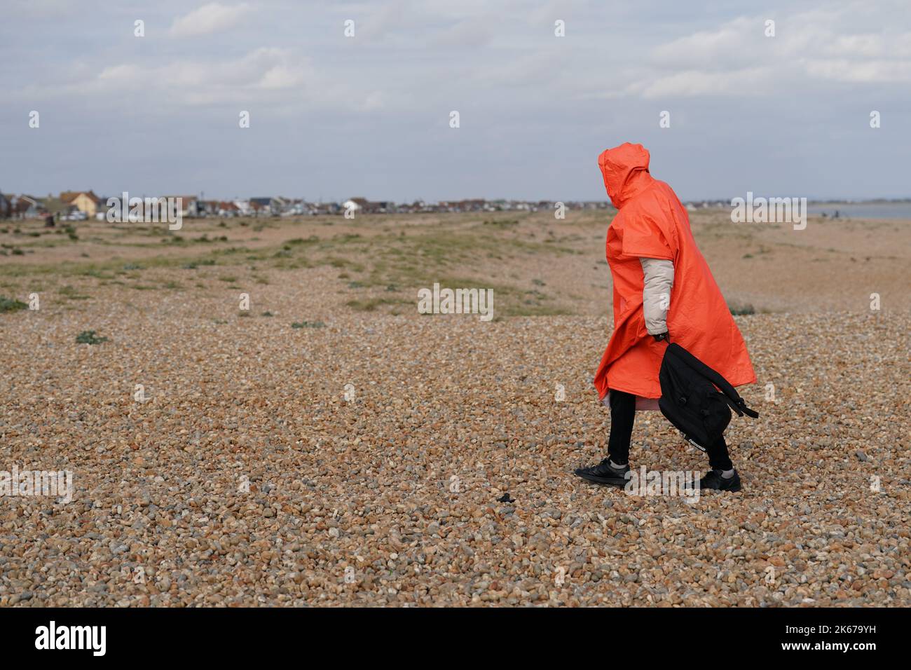 Ein Mann, der als Migranten gedacht wurde, geht über den Dungeness Strand, nachdem er vom Dungeness Rettungsboot nach einem Vorfall mit einem kleinen Boot im Kanal gebracht wurde. Bilddatum: Mittwoch, 12. Oktober 2022. Stockfoto