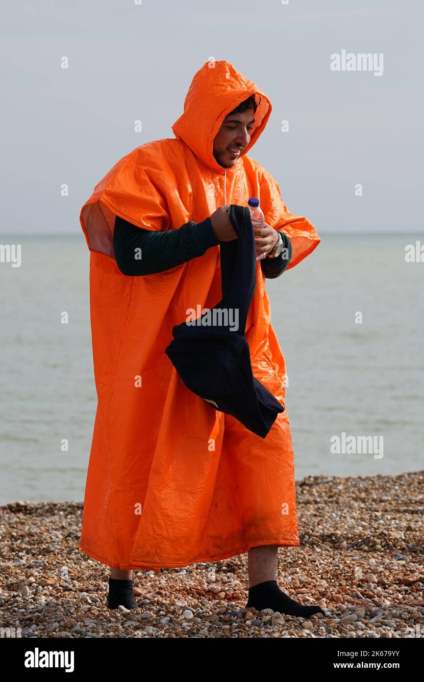 Ein Mann, der als Migranten gedacht wurde, geht über den Dungeness Strand, nachdem er vom Dungeness Rettungsboot nach einem Vorfall mit einem kleinen Boot im Kanal gebracht wurde. Bilddatum: Mittwoch, 12. Oktober 2022. Stockfoto