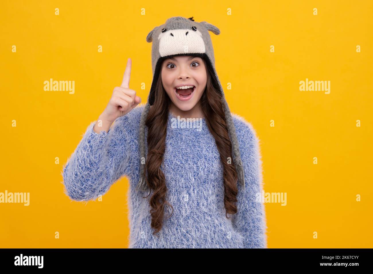 Modernes Teenager-Mädchen 12, 13, 14 Jahre alt trägt Pullover und Strickmütze auf isoliertem gelben Hintergrund. Aufgeregt Teenager Mädchen. Stockfoto