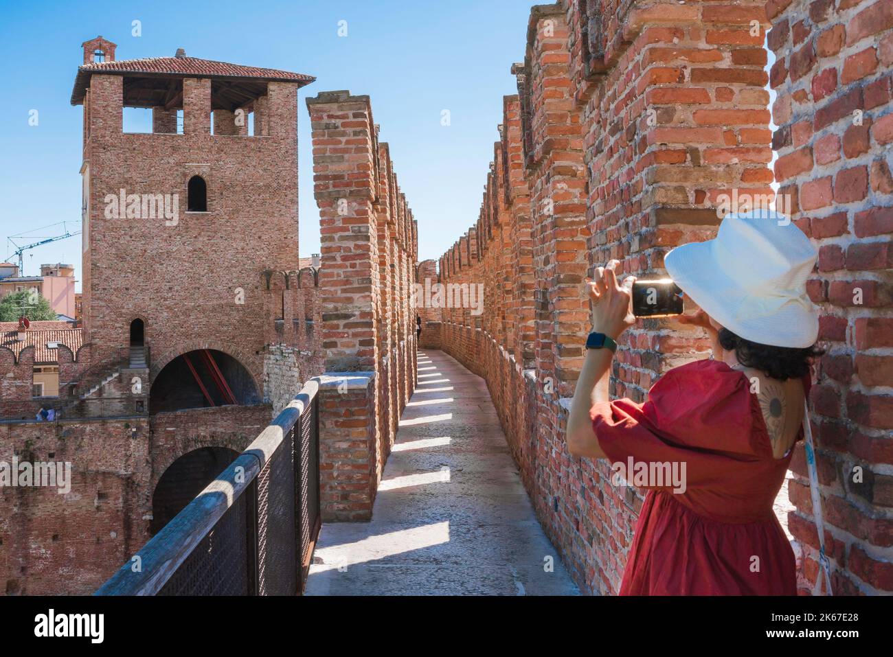 Weibliche Touristin, Rückansicht im Sommer einer jungen Touristin, die ein Foto der Festungsmauern des Castelvecchio in Verona, Italien, macht. Stockfoto