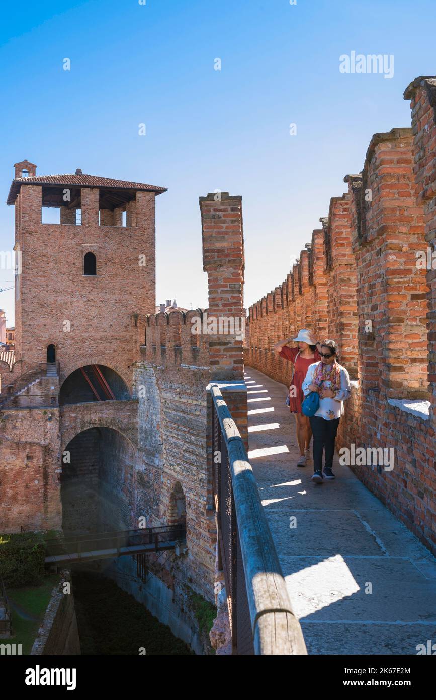 Touristen Burg, Blick im Sommer von zwei weiblichen Touristen auf einem Fußweg erkunden die mittelalterlichen Zinnen des Castelvecchio, Verona, Italien Stockfoto