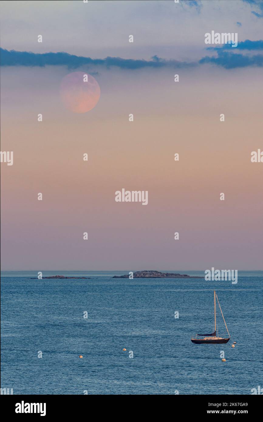 96% beleuchteter Hunters Moon Peeking through the Clouds einfarbig verankertes Segelboot & Inseln Stockfoto