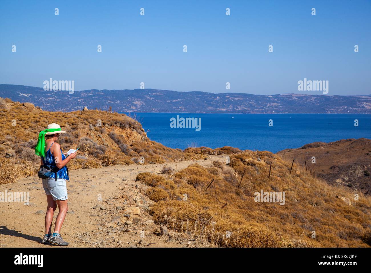 Frau, die in den Hügeln über dem griechischen Ferienort Molyvos auf der Insel Lesvos Griechenland über der Ägäis in Richtung Türkei spazierend ist Stockfoto