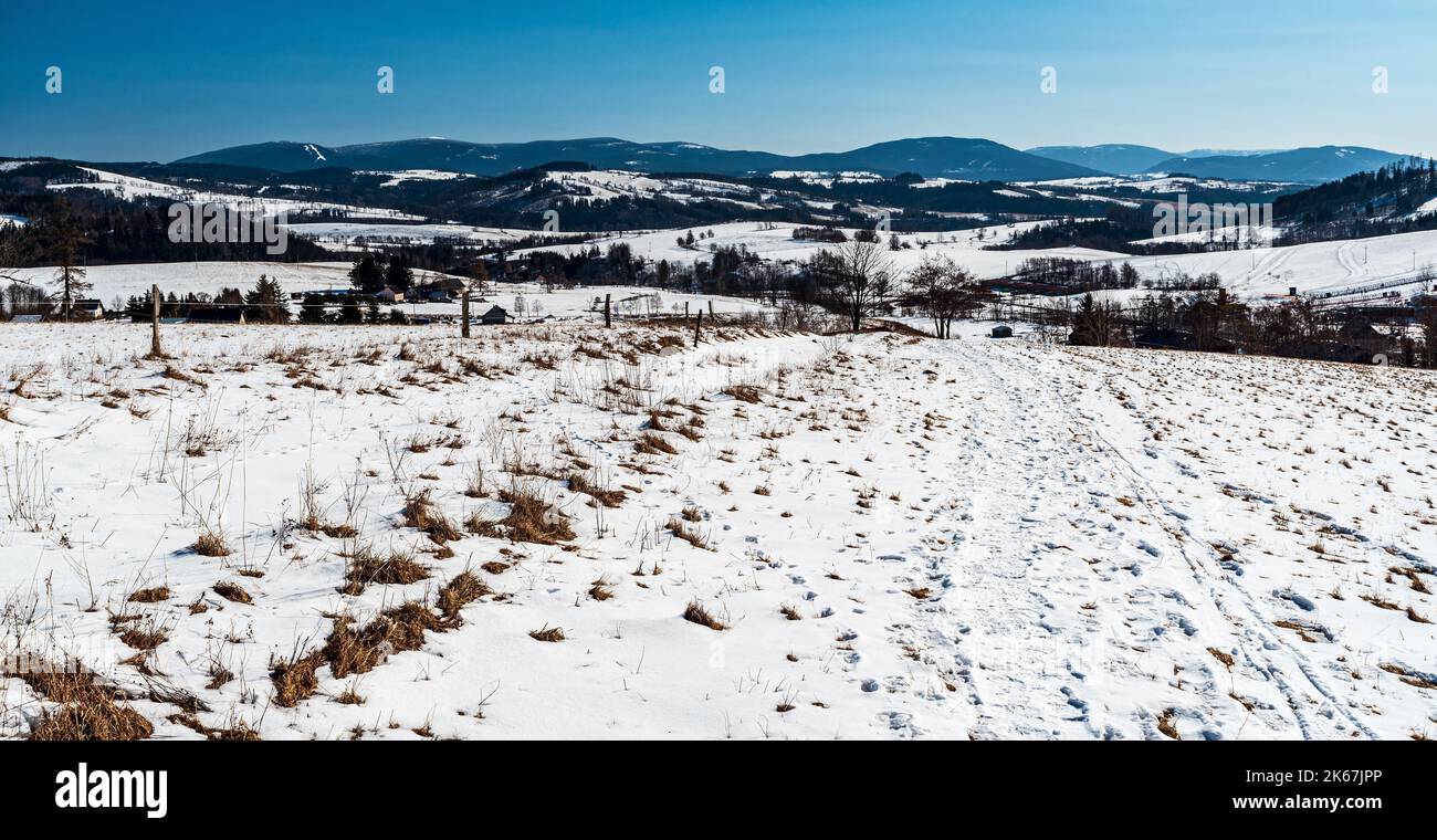 Hrub Jesenik und näher unteren Hügeln der Rychlebske hory Berge von der Wiese über Stribrnice Dorf in der Tschechischen republik während schönen Wintertag Stockfoto