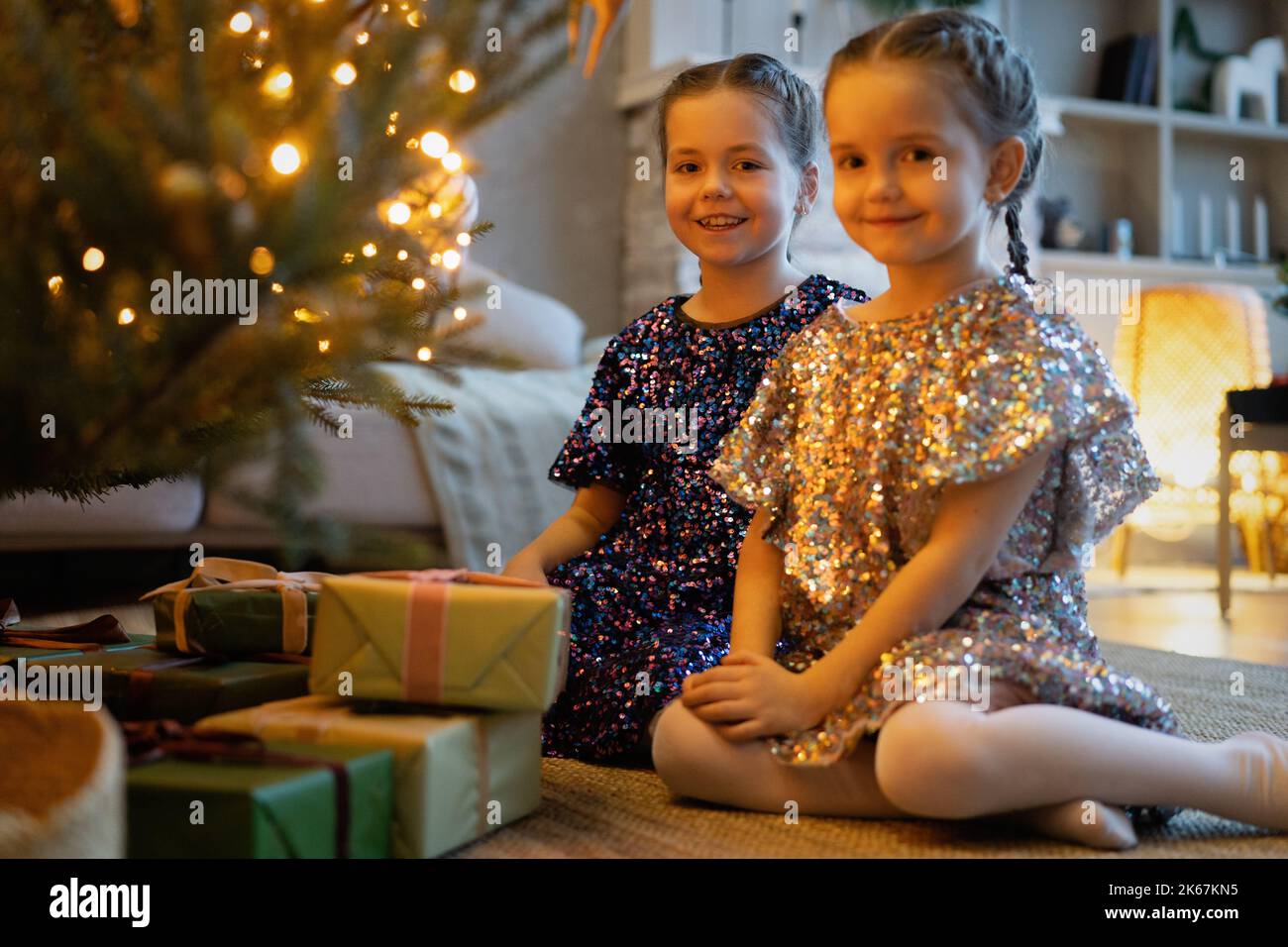 Zwei niedliche kleine Mädchen unter dem Weihnachtsbaum. Kinder unter Weihnachtsbaum mit Geschenkschachteln. Neujahrsschmuck. Schwestern Stockfoto