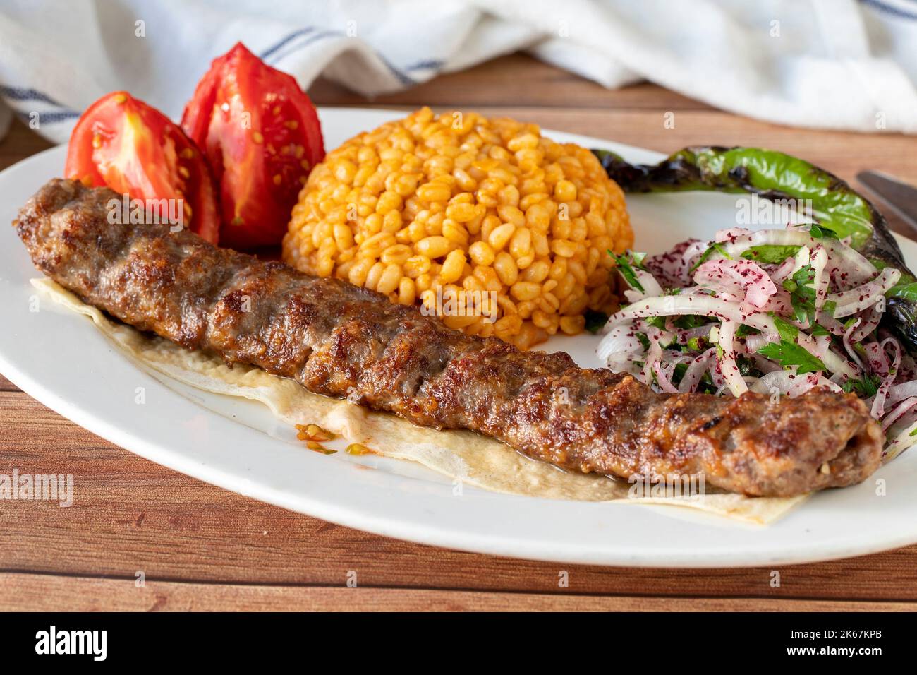 Adana Kebab auf Holzhintergrund. Traditionelle türkische Kebab-Delikatessen. Nahaufnahme Stockfoto