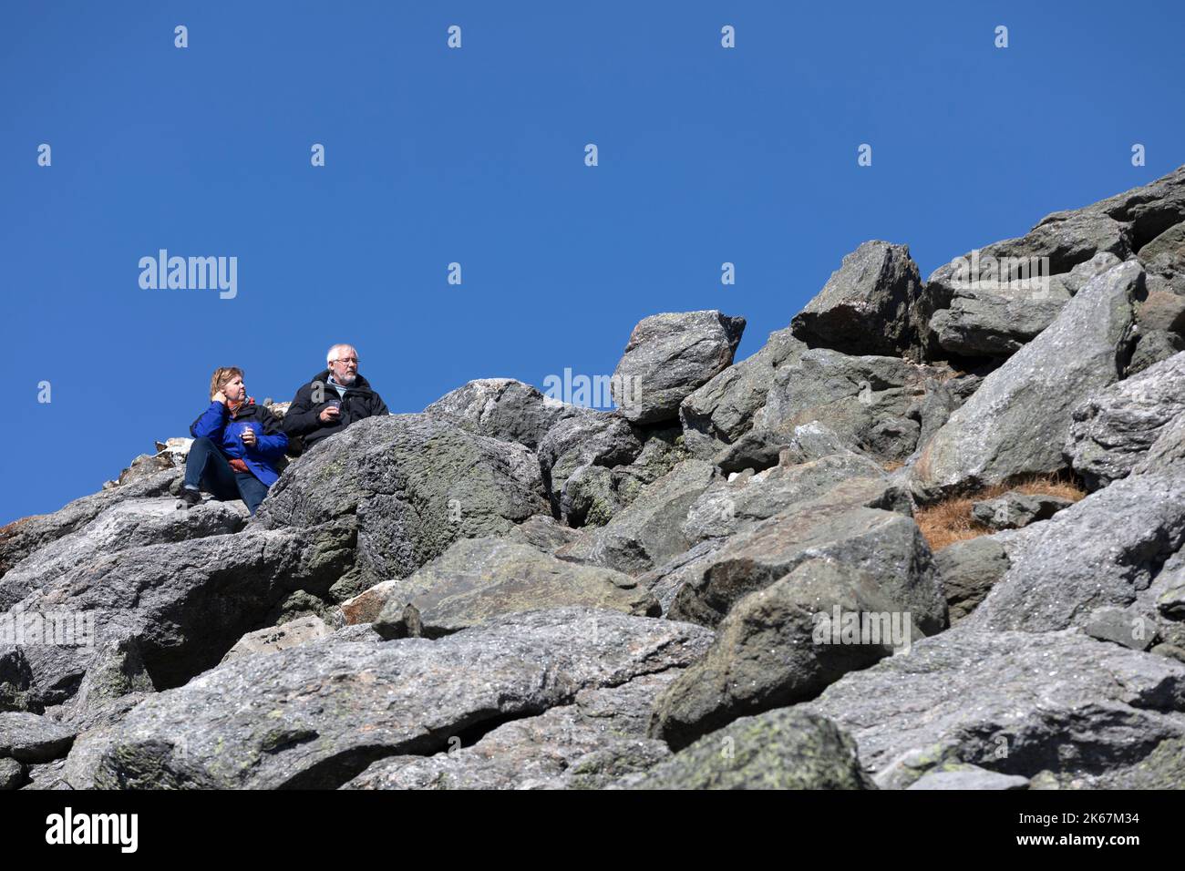 Paar sitzen auf einem felsigen Hang auf dem Gipfel des Mount Washington, White Mountain National Forest Stockfoto