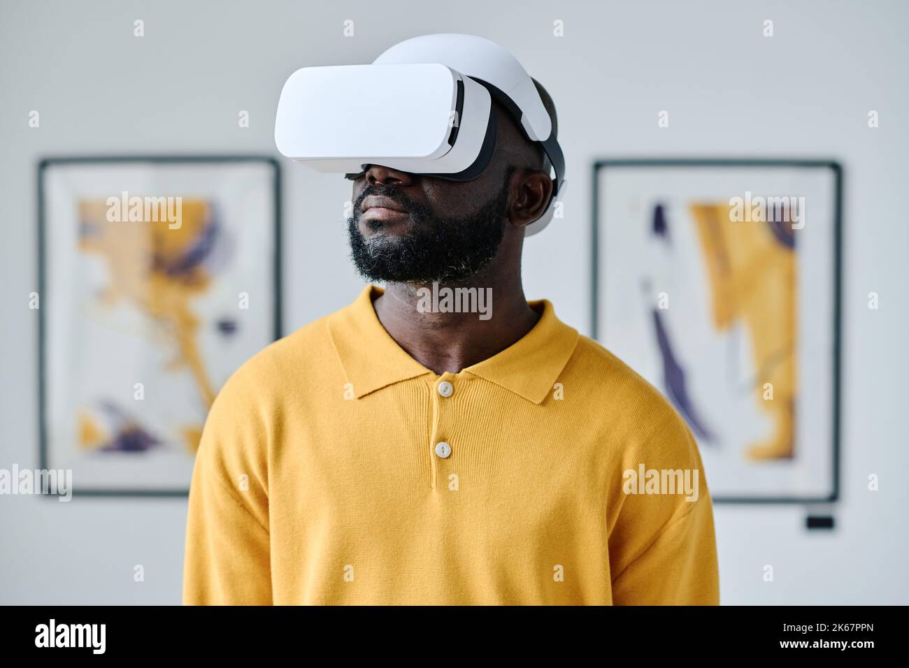 Afrikanischer junger Mann in Virtual-Reality-Brille, Besuch der Galerie für moderne Kunst Stockfoto