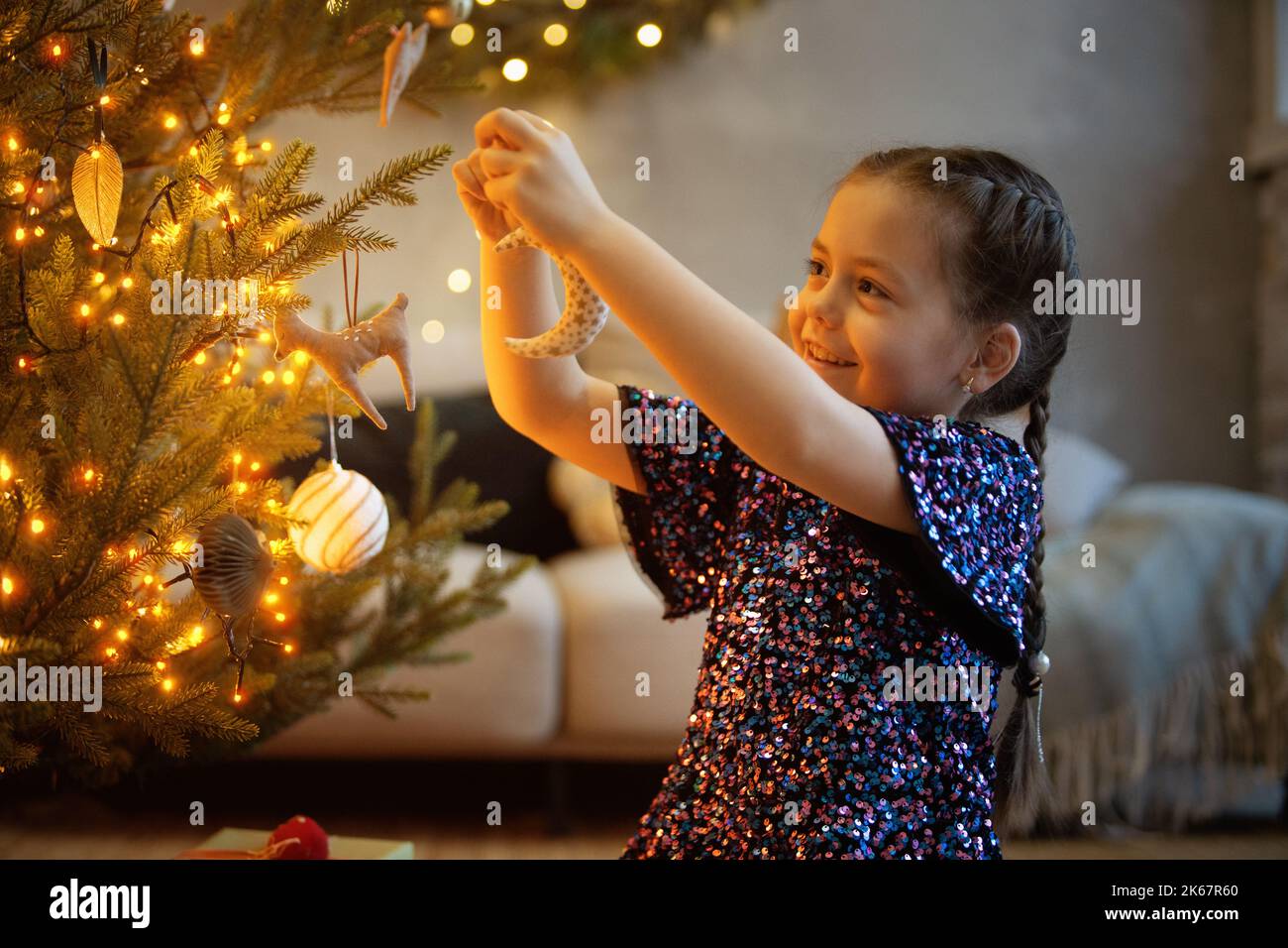 Winterferien und Menschen Konzept - glückliches kleines Mädchen Dekoration weihnachtsbaum zu Hause. Stockfoto