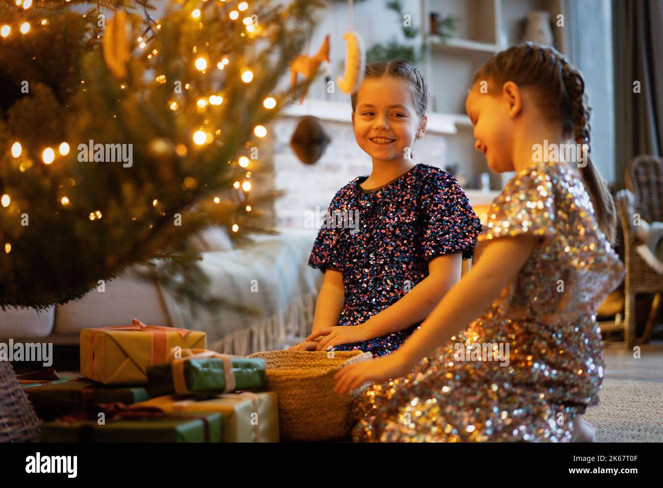 Zwei Schwestern spielen in der Nähe des Weihnachtsbaums und Geschenke. Glückliche kleine Mädchen schmücken weihnachtsbaum zu Hause Stockfoto