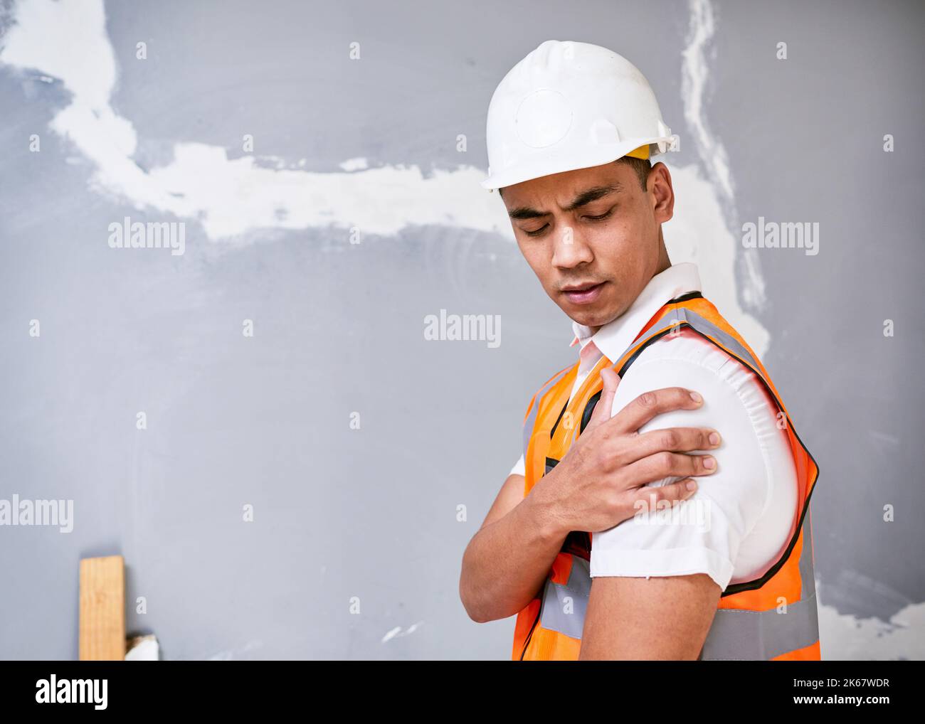 Bauarbeiter hält die Schulter bei Schmerzen durch Verletzungen am Arbeitsplatz auf der Baustelle Stockfoto