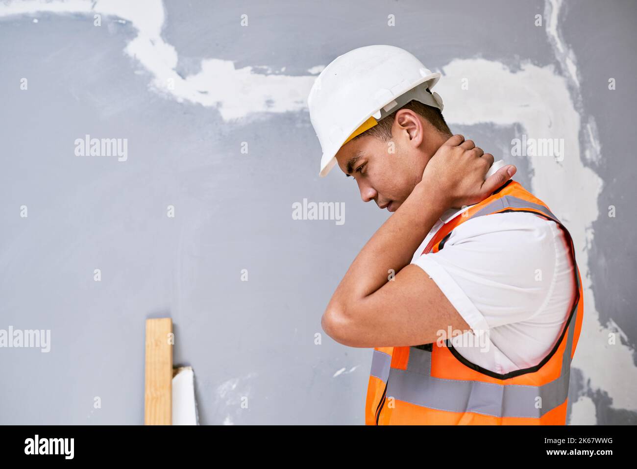 Ein junger asiatischer Bauarbeiter hält seinen Hals vor Schmerzen durch Verletzungen am Arbeitsplatz Stockfoto