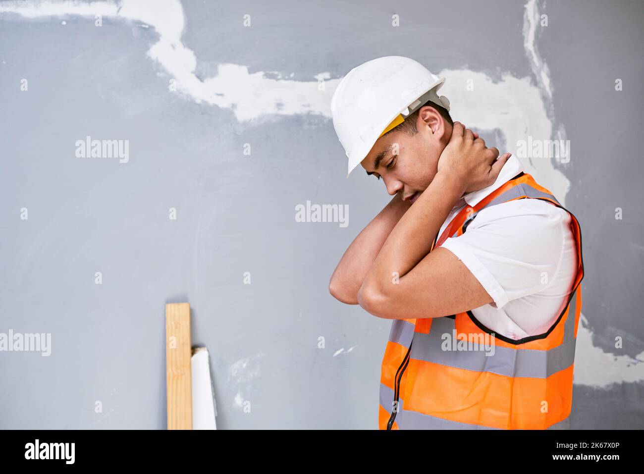 Ein junger asiatischer Bauarbeiter hält seinen Hals vor Schmerzen durch Verletzungen am Arbeitsplatz Stockfoto